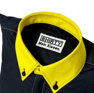 a black shirted pillow with a yellow collar and label