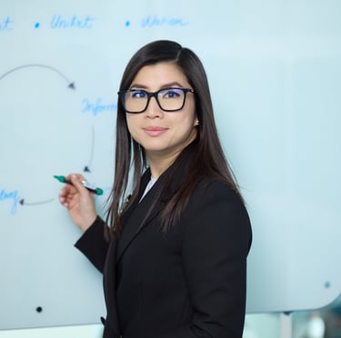 a woman in a suit and glasses is standing in front of a white board