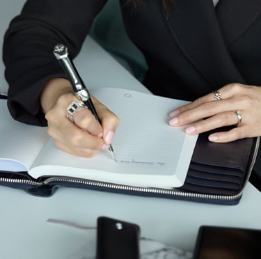 a woman in a suit writing on a notebook