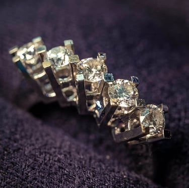 Close-up of diamond wedding rings on a dark fabric background, captured by Fred Art Studio.