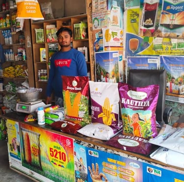 Shopkeeper at an Indian agriculture store with hybrid corn and vegetable seeds for farming.