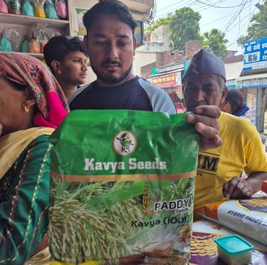 A merchant holds a bag of Kavya Seeds Paddy rice seeds in a busy Indian agricultural market.