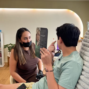 A medical professional in a face mask provides a patient consultation for facial aesthetics and skin treatment.