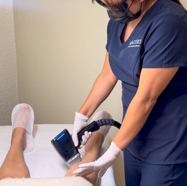 Professional technician performing a laser hair removal treatment on a patient's leg in a medical spa.