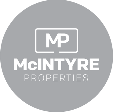 McIntyre Properties real estate agency logo in white text on a grey circular background.