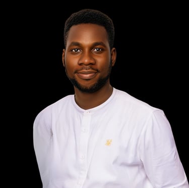 Professional portrait of a smiling Black man in a white long-sleeve shirt against a black background.