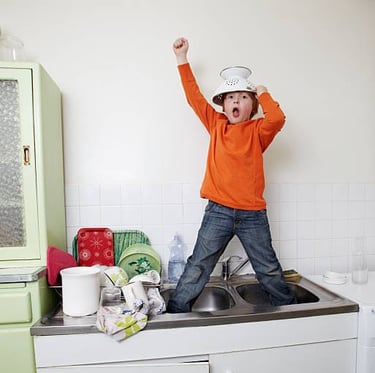 a young boy standing in joy in a kitchen sink