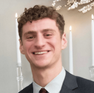 a man in a suit and tie smiling for the camera
