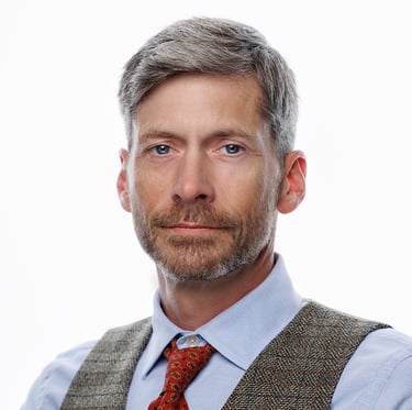 Headshot of an handsome  man with a beard on bright white backdrop.