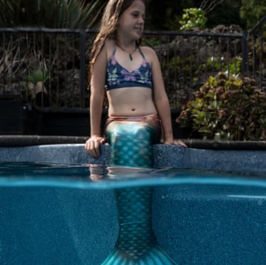 Mermaid sitting in her tail on the pools edge