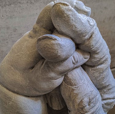 A marble sculpture of a child's hand embracing the relaxed hand of an elderly person