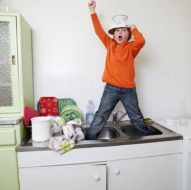 a young boy standing in joy in a kitchen sink
