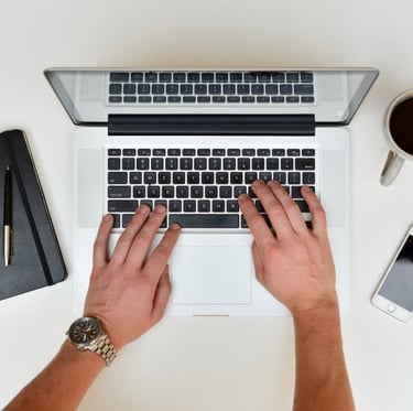 a person's hands typing on a laptop computer