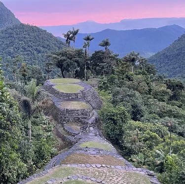 Ancient stone terraces of Ciudad Perdida (Lost City) in Colombia at sunset with lush jungle mountains.