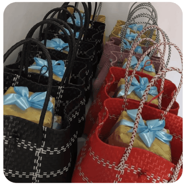 Custom handmade woven plastic bags in black and red prepared for event souvenir distribution.