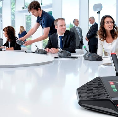 Modern conference room with participants using Bosch discussion system microphones, including touchscreens and LED indicators