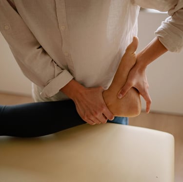 Une femme est allongée sur une table de massage, tandis qu'un thérapeute lui prodigue des soins.