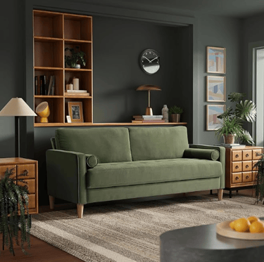 green velvel sofa with wound pillar pillows and thin wooden legs