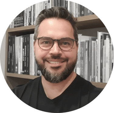 Consultor de valuation e avaliação de empresas de óculos sorrindo em frente à uma estante de livros