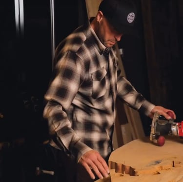 Basile in a plaid shirt and a hat is making a Mended Heart