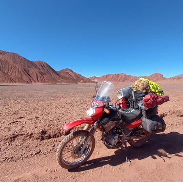 a motorcycle parked in the desert with a backpack on it cono de arita puna atacama salar