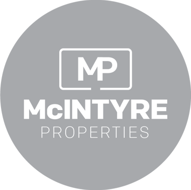 McIntyre Properties real estate agency logo in white text on a grey circular background.
