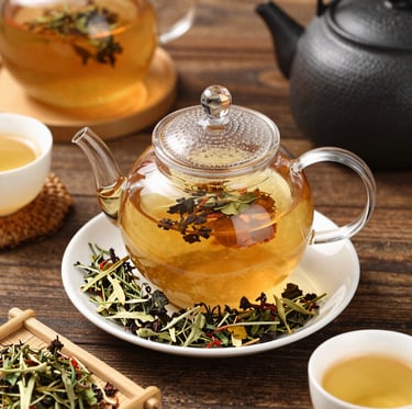 A cozy scene of a steaming cup of herbal tea surrounded by fresh herbs and dried leaves on a rustic wooden table.