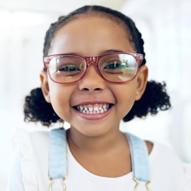 Little girl smiling and wearing a kid's glasses