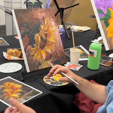 a man is painting a picture of a sunflower at an art-ish event