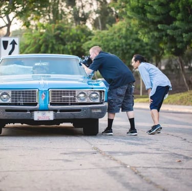 A cameraman and a director filming a classic car