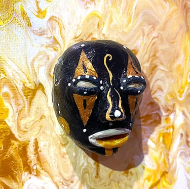 Ilona Paris tableune sculpture noir ressemblant à un masque qui émerge d'un tableau jaune vu de près