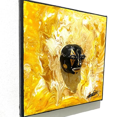 Ilona Paris tablune sculpture noir ressemblant à un masque qui émerge d'un tableau jaune vu de côtés