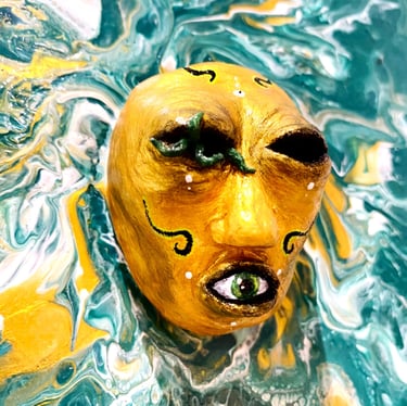une sculpture sans yeux avec un oeil dans la bouche qui émerge d'une toile verte vu de près