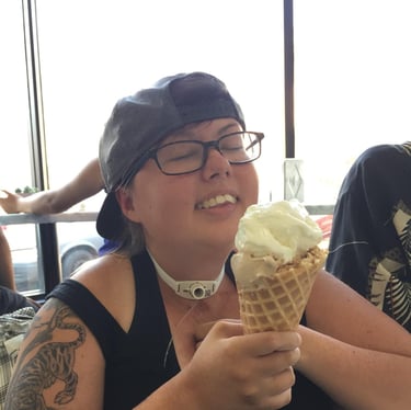 Photo of Stacey enjoying a ice cream cone. Her head is back with a big smile, her tattoo is visible