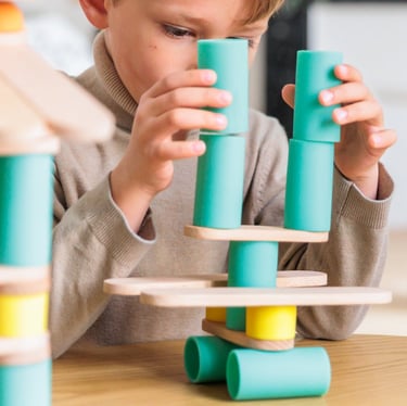 A boy creating a structure from colorful silicone and wooden figures in the room
