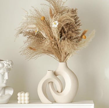 Minimalist beige interlocking ceramic donut vases with dried pampas grass and flowers.