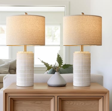 Pair of textured white ceramic table lamps with linen shades on a wooden console table.