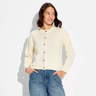 A smiling woman wearing a cream button-up cardigan sweater from wild fable target