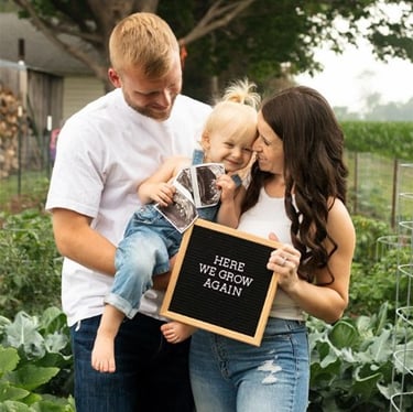 couple holding toddler announcing 2nd pregnancy