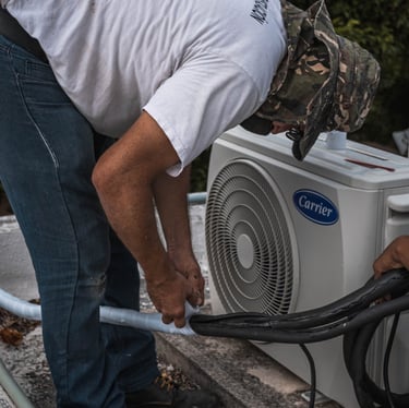 An AC technician joining the pipes of an ac unit together using adhesive tape, ensuring a tight and secure connection.