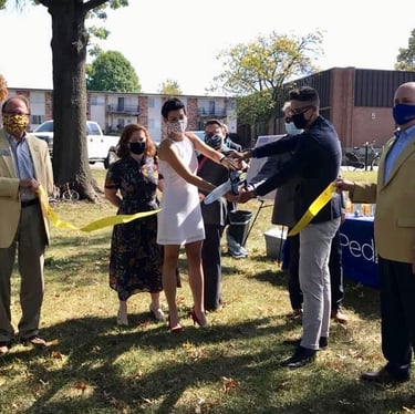 Group of people cutting ribbon with large scissors