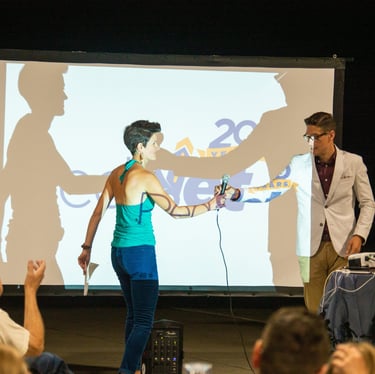 Man in white jacket passing microphone to woman in green shirt
