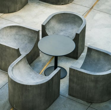 Mobilier d'extérieur moderne composé de quatre fauteuils en béton arrondis et une petite tabl