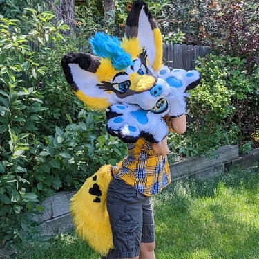 A yellow coyote fursuit featuring a full jaw set of silicone teeth and big ears as well as glow in the dark parts From Teto