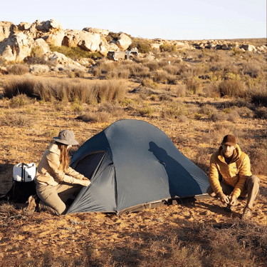 a man and woman setting up a tent