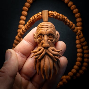 Hand-carved wooden head pendant with a detailed beard held near a Rudraksha bead necklace.