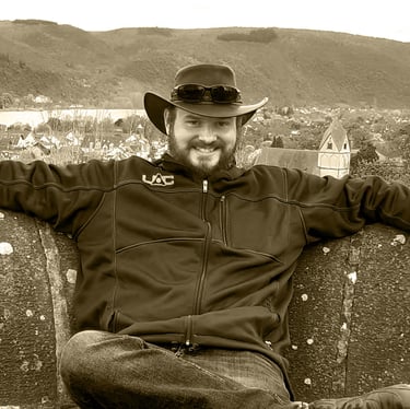 a man in a cowboy hat sitting on a bench, Vaughan Farrar, Author, Rhens, The kings chair Königsstuhl
