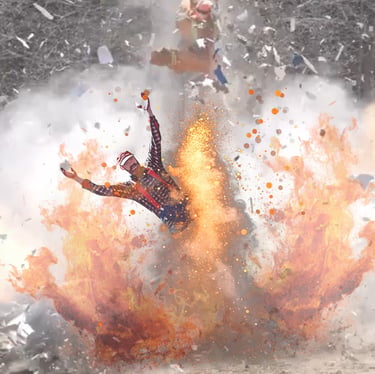 Hank in a red flannel shirt thrown by a large cinematic fire explosion with debris in the air.