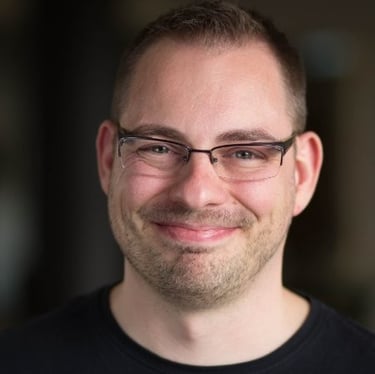 Richard Stevens smiling, wearing  glasses and a black shirt