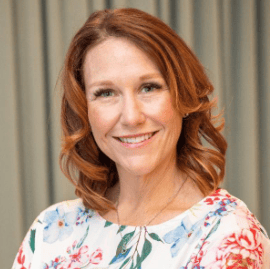 a woman with red hair and with a flowered dress smiling